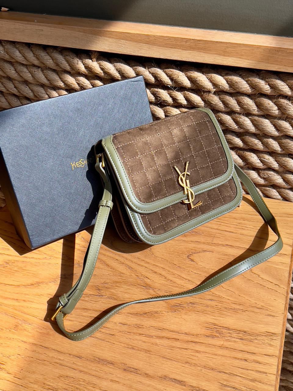 TanYves Saint Laurent YSL Premium Shoulder Bag and green handbag with a visible brand logo on a wooden surface.