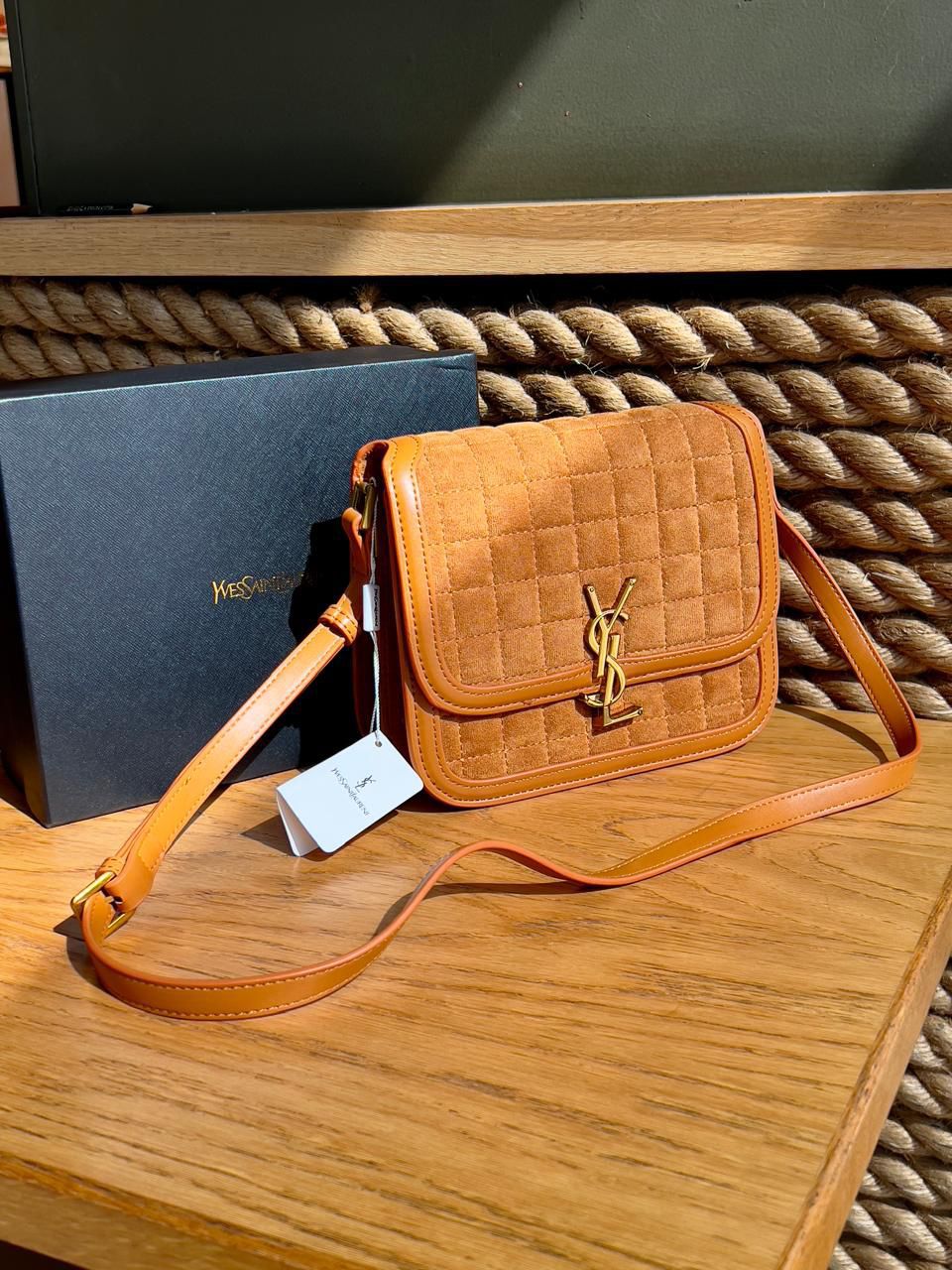 Brown Yves Saint Laurent YSL Premium Shoulder Bag quilted handbag with a brand logo on a wooden surface next to a branded box.