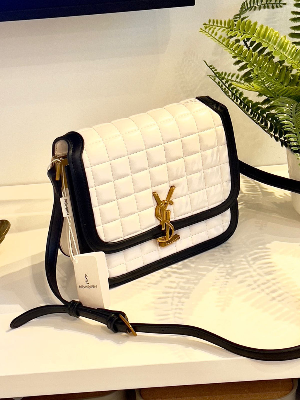 White Yves Saint Laurent YSL Premium Shoulder Bag quilted handbag with black accents and a gold logo on a white surface.
