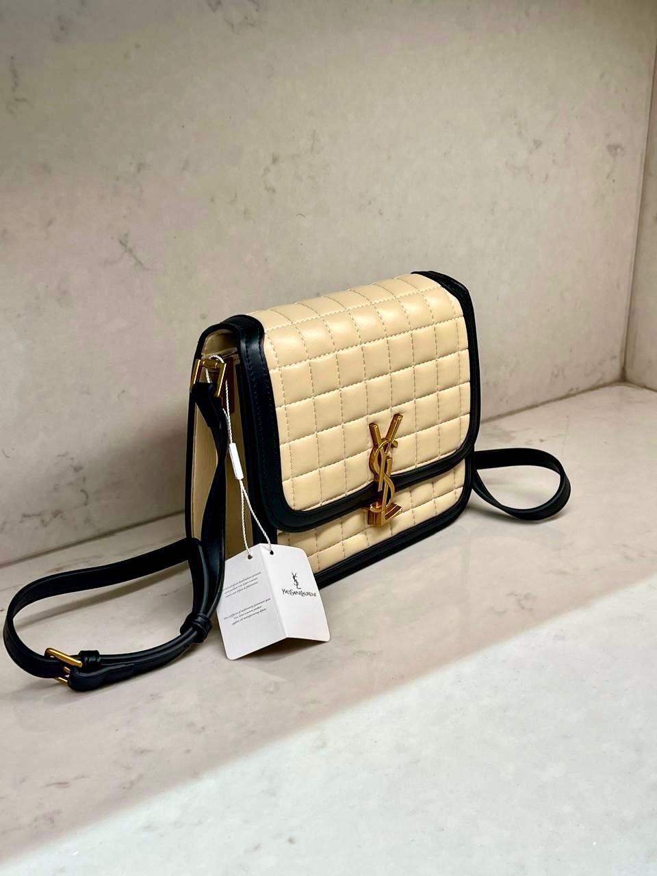 Beige Yves Saint Laurent YSL Premium Shoulder Bag quilted handbag with black accents and a gold tag on a light gray surface.