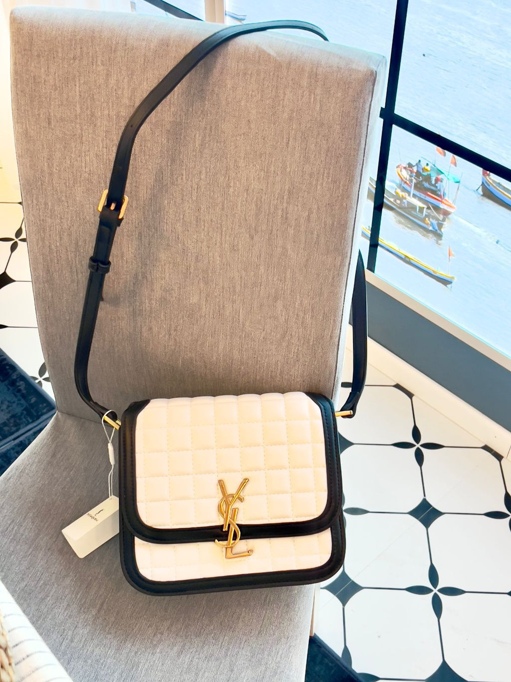 White Yves Saint Laurent YSL Premium Shoulder Bag quilted handbag with black accents on a mannequin in a store setting.