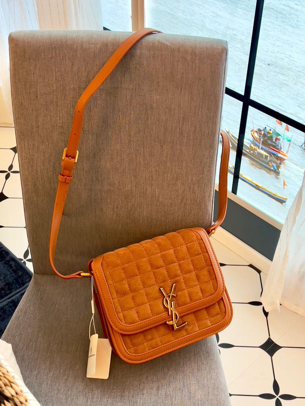 Brown Yves Saint Laurent YSL Premium Shoulder Bag quilted handbag with a brand logo on a mannequin bust in a room with a window view.