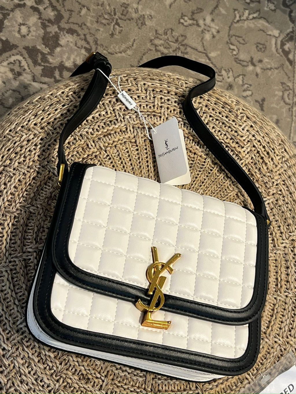 White Yves Saint Laurent YSL Premium Shoulder Bag quilted handbag with black trim and gold logo on a textured surface