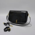 Black Yves Saint Laurent (YSL) Shoulder Bag  handbag with gold accents on a checkered surface, accompanied by a strap and papers.