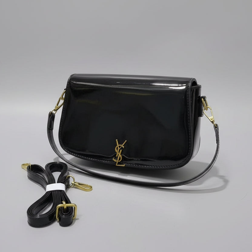 Black Yves Saint Laurent (YSL) Shoulder Bag  handbag with gold accents on a checkered surface, accompanied by a strap and papers.