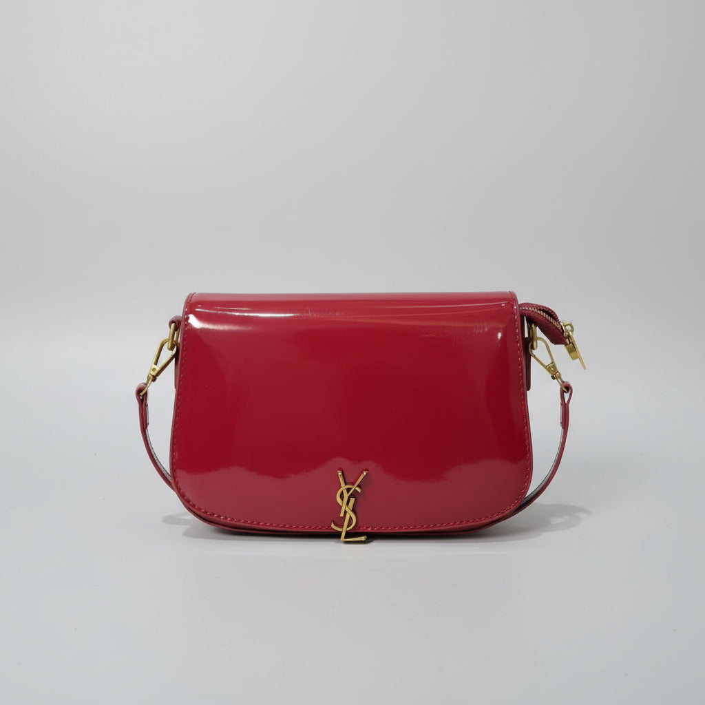 Red Yves Saint Laurent (YSL) Shoulder Bag  handbag with a brand logo on a surface with other items.