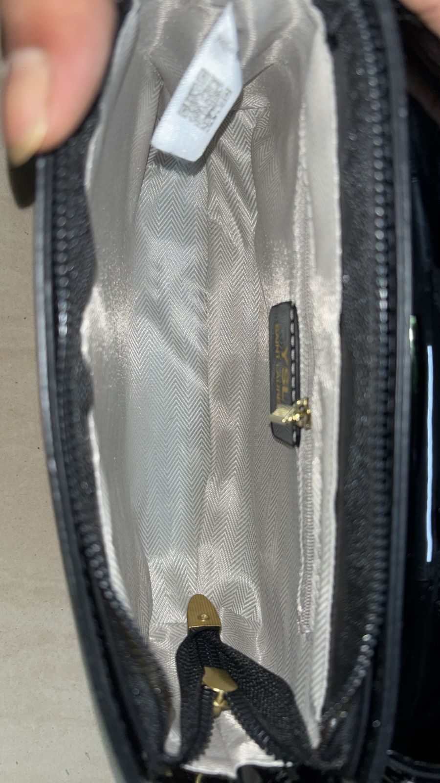 Black Close-up of a black handbag with gold zippers and a visible brand tag.