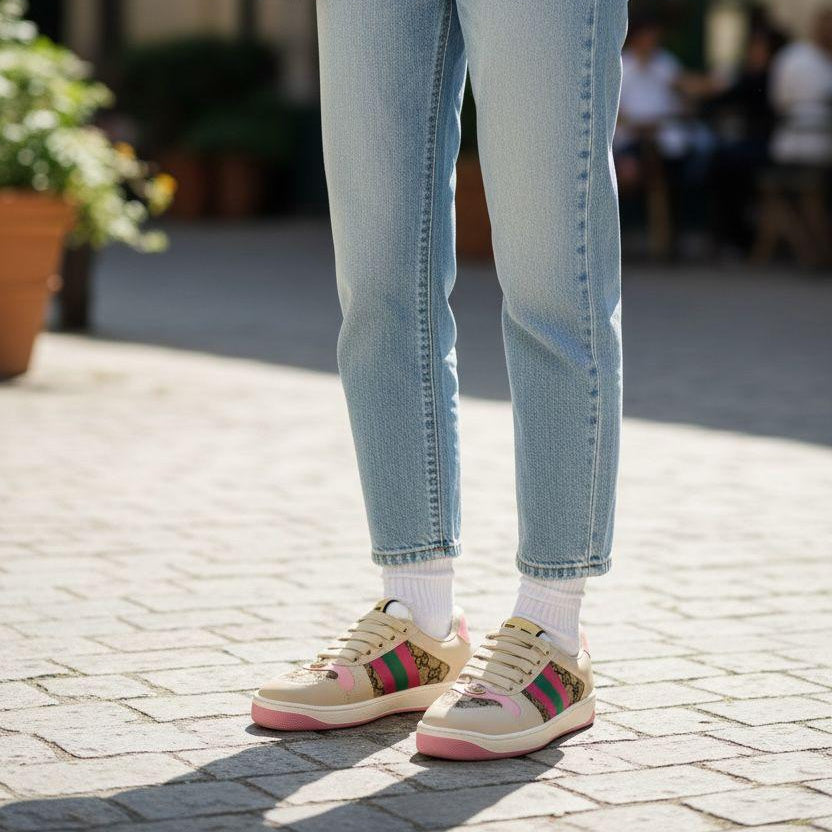 Gucci Women’s Premium Sneakers Person wearing a pink sweater, light blue jeans, and colorful sneakers on a paved outdoor area.