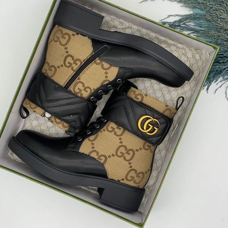 Brown Gucci boots in a box with Gucci logo.