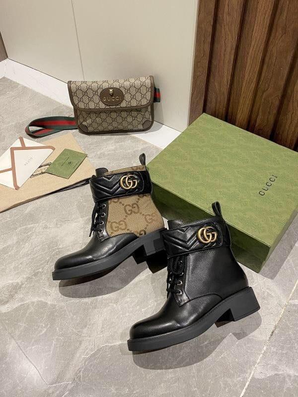 Black leather boots with Gucci logo on a marble floor with Gucci bag and box.