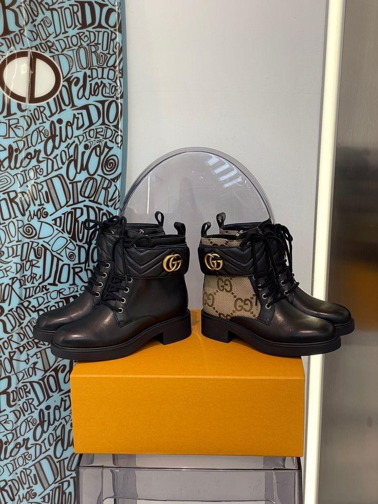 Black Gucci Women’s Premium Leather Boots with Brand Box boots with a brand logo on a yellow box against a patterned wall.