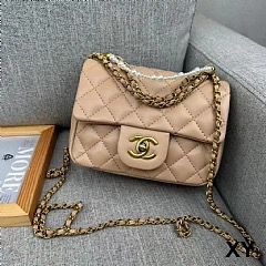 Beige Chanel Mini Flap handbag with gold chain on a gray couch