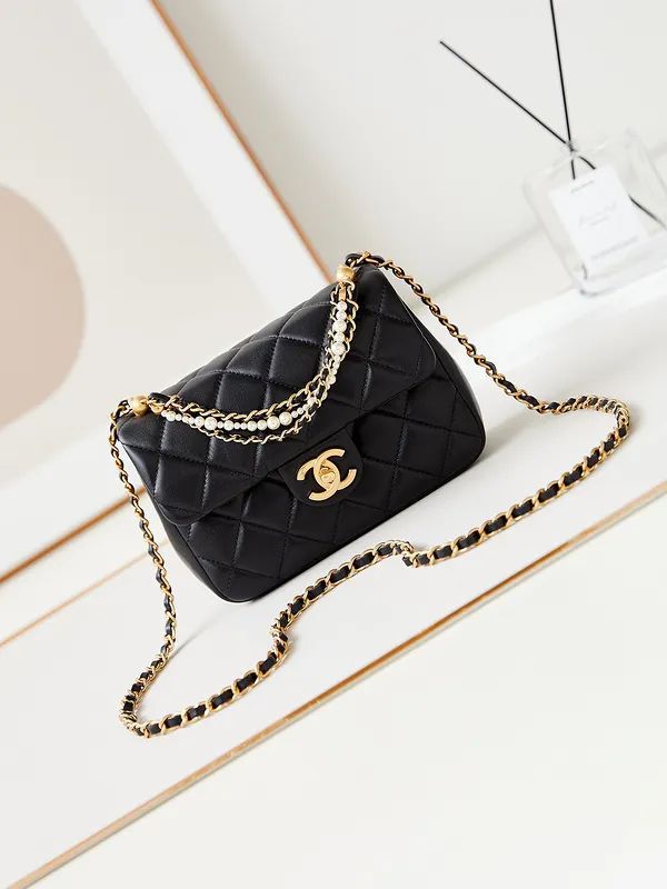 Black Chanel Mini Flap Bag quilted handbag with gold chain on a light wooden surface