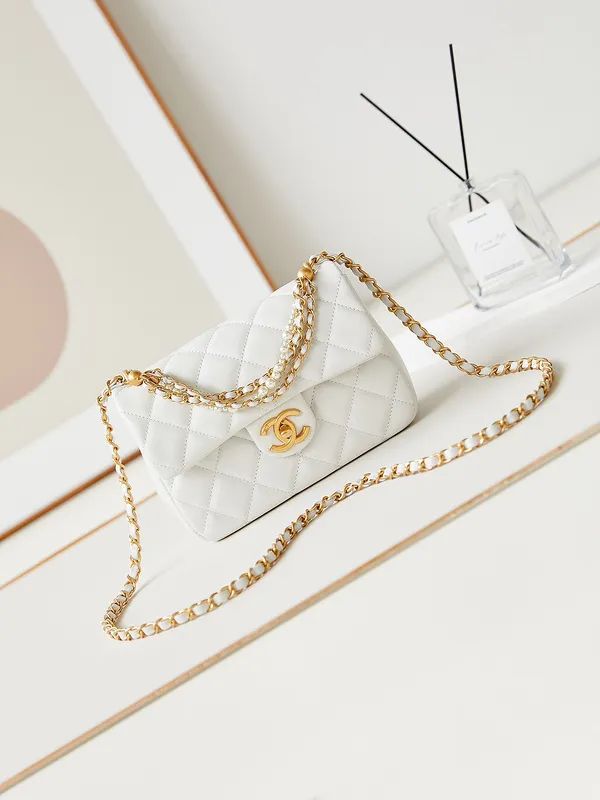 White Chanel Mini Flap Bag quilted handbag with gold chain on a light wooden surface