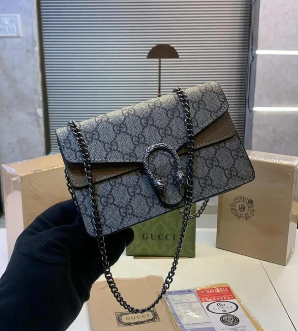 Beige Gucci Dionysus Mini .Gucci handbag with chain strap held by a hand, with Gucci packaging in the background.