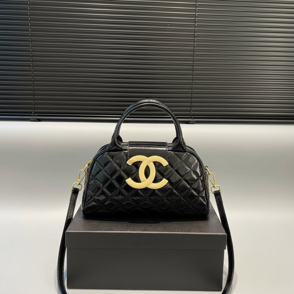 Black quilted Chanel Women’s Large Capacity Fashion Handbag .Black quilted handbag with yellow logo on a gray box against a metallic background