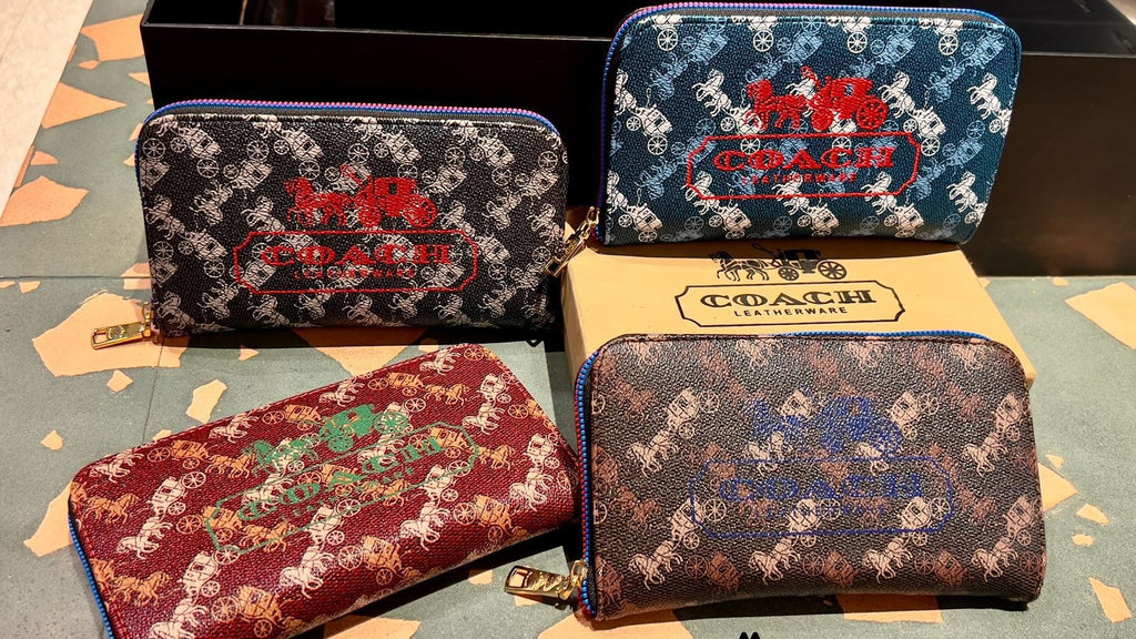 Four Coach wallets with different patterns on a surface