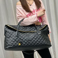 Black YSL Giant Quilted Leather Weekend Duffle Bag. Person holding a black quilted handbag with a visible brand logo against a plain background