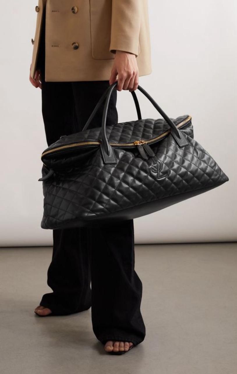 Black YSL Giant Quilted Leather Weekend Duffle Bag Person holding a black quilted handbag against a neutral background