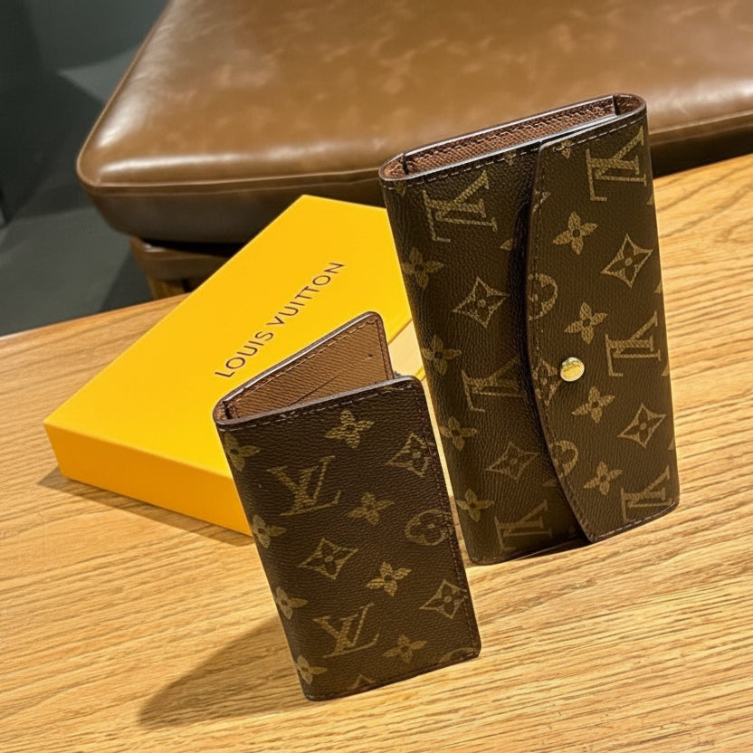 Brown Louis Vuitton wallet and cardholder on a wooden surface with a yellow box in the background.