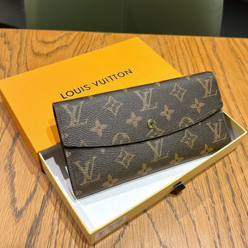 Tan Louis Vuitton wallet in a box on a wooden surface