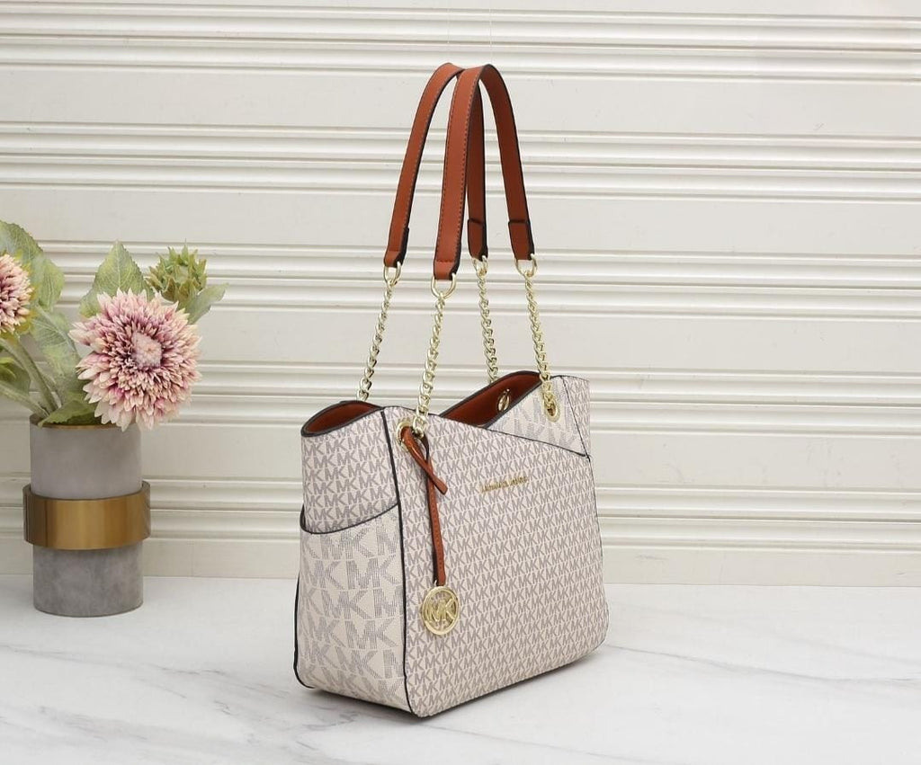 White Michael Kors Signature Tote Bag Designer handbag with floral arrangement on a light wooden surface