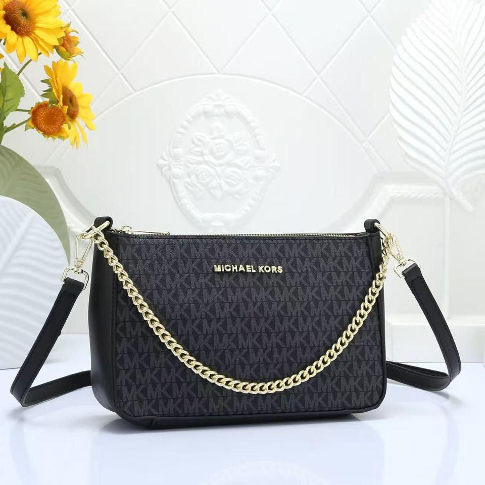 Black Michael Kors Chain Sling Bag handbag with gold chain detail on a white surface with sunflowers in the background