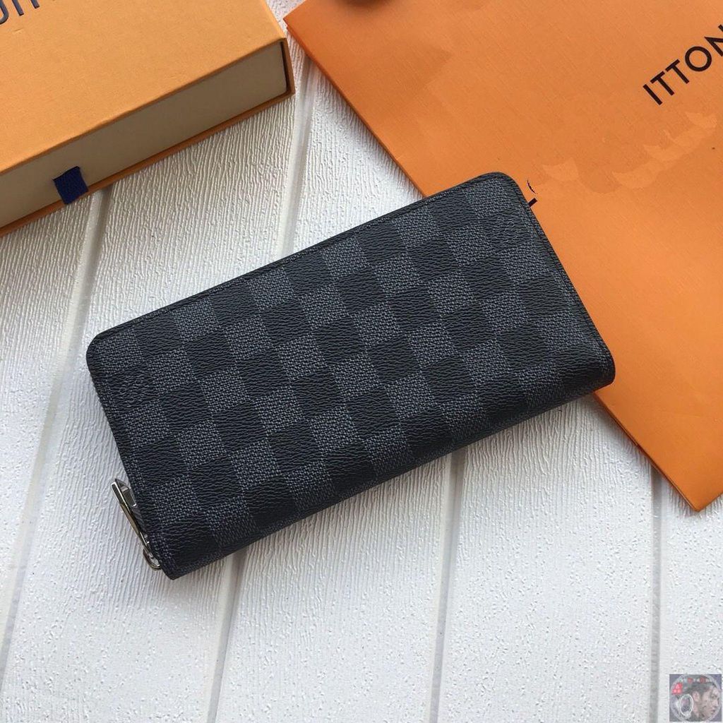 Black checkered Louis Vuitton Premium Zipper Wallet on a white surface with orange background