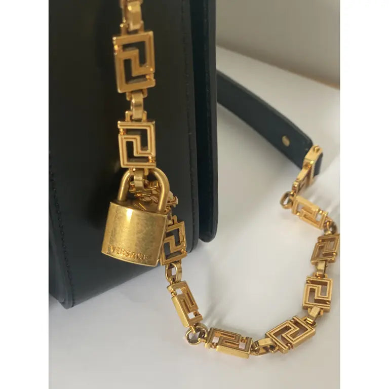 Black medusa Gold chain necklace with a lock pendant on a white surface