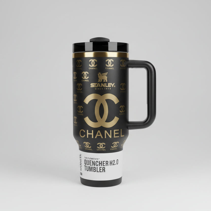 Black tumbler with gold branding against a background of fashion brand names