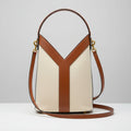 Beige YSL Y Top Handle Bucket Bag Handbag with a distinctive Y-shaped design on a white surface with a black and gold striped background.