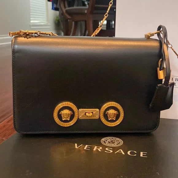 Black medusa Versace handbag with gold accents on a Versace box.